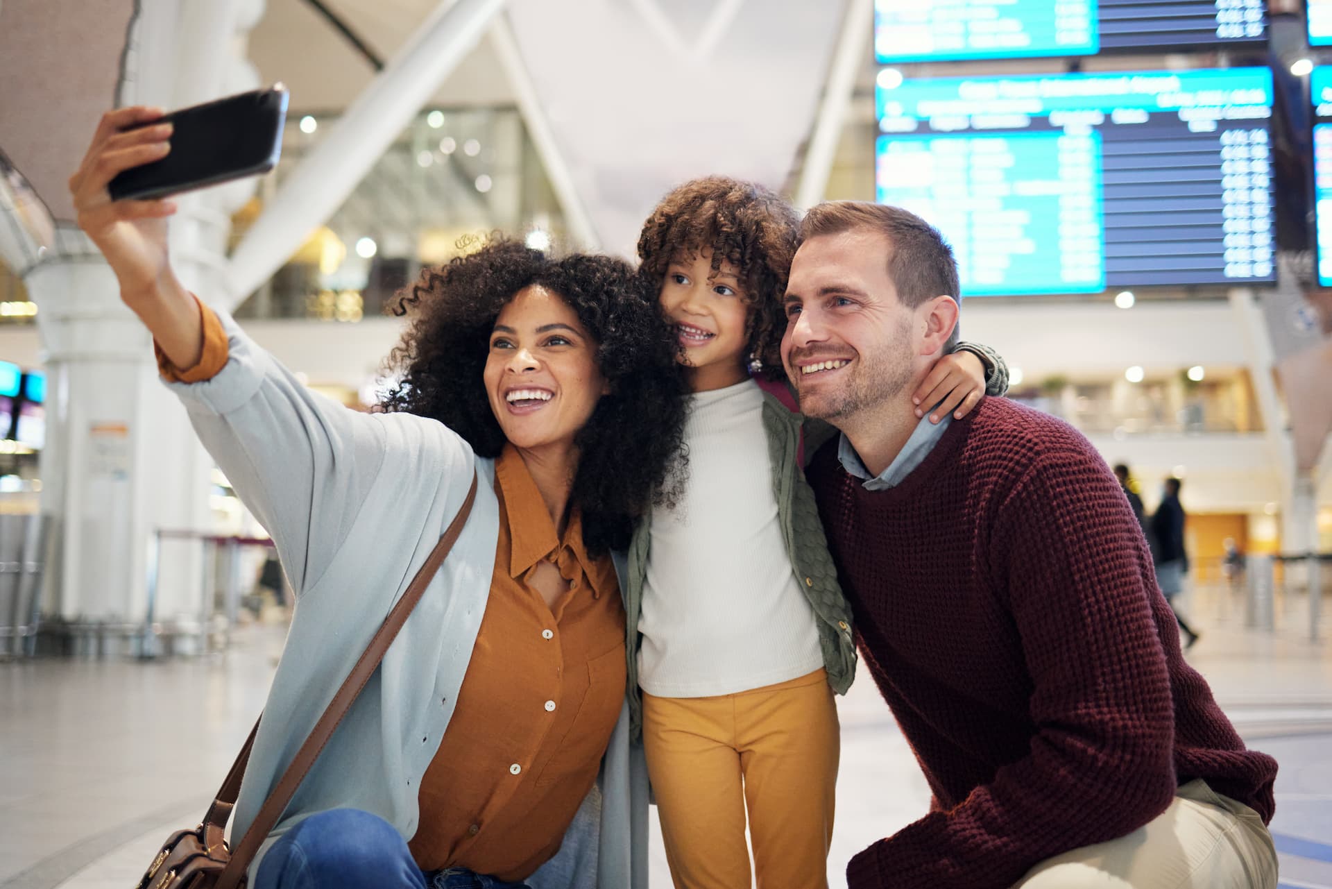 A family joyfully taking a selfie at the airport, capturing their travel excitement and memories before their journey