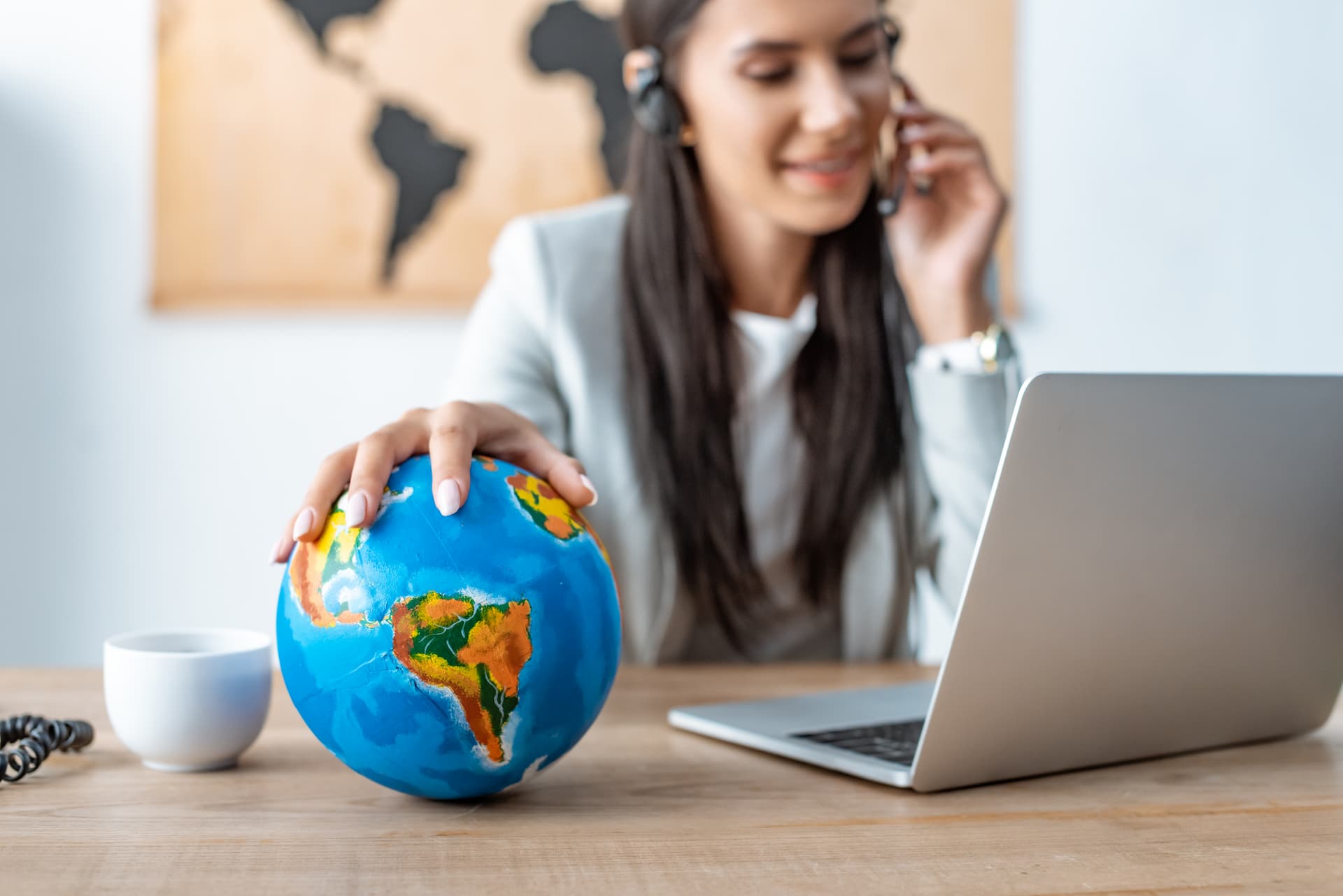 A travel customer support agent wearing a headset and holding a globe, showcasing global expertise