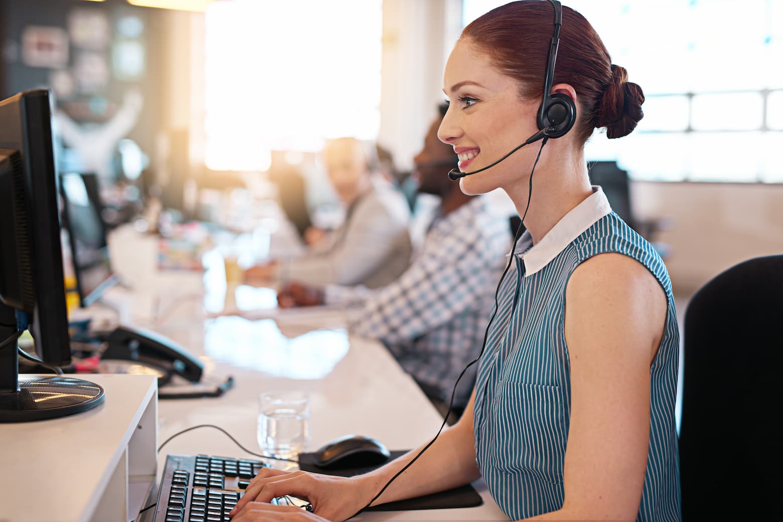 A smiling female customer support agent wearing a headset, engaging in a friendly conversation, representing efficient, customer-focused service