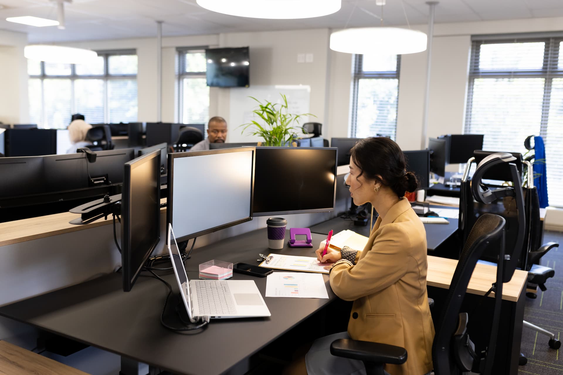 Asian woman sitting at desk and working on computer with copy space in office