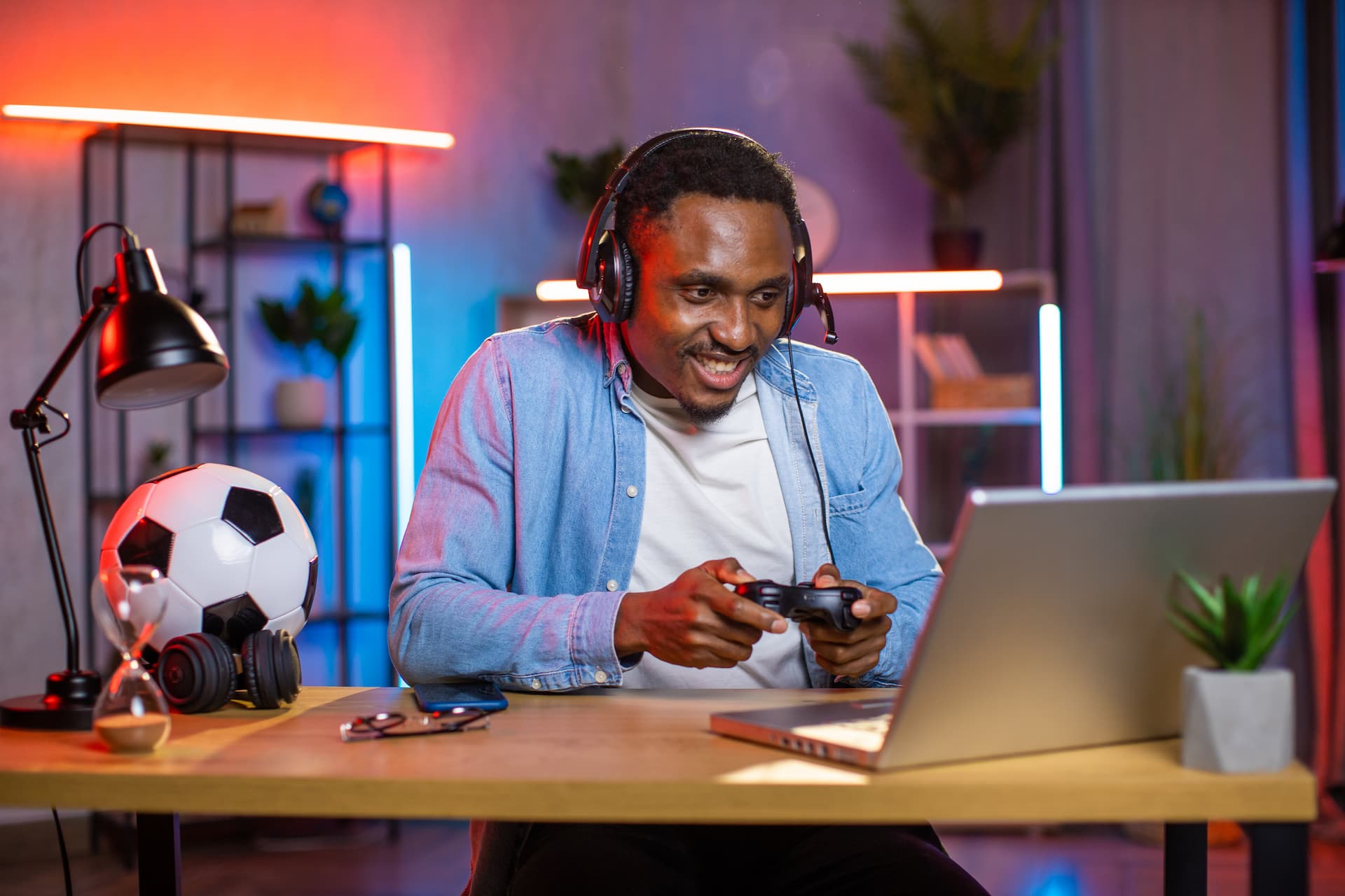 Excited black man in headset playing video games on laptop