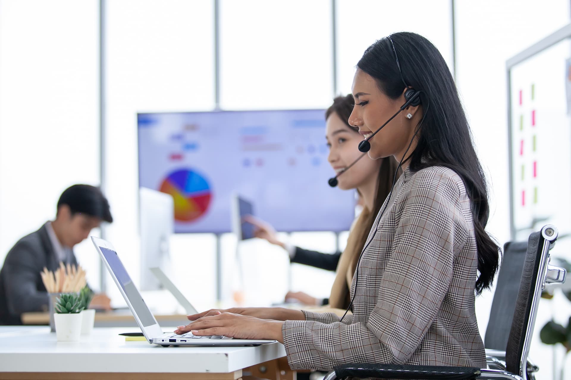 Female operator agent with headsets and her team working in a call center customer service office
