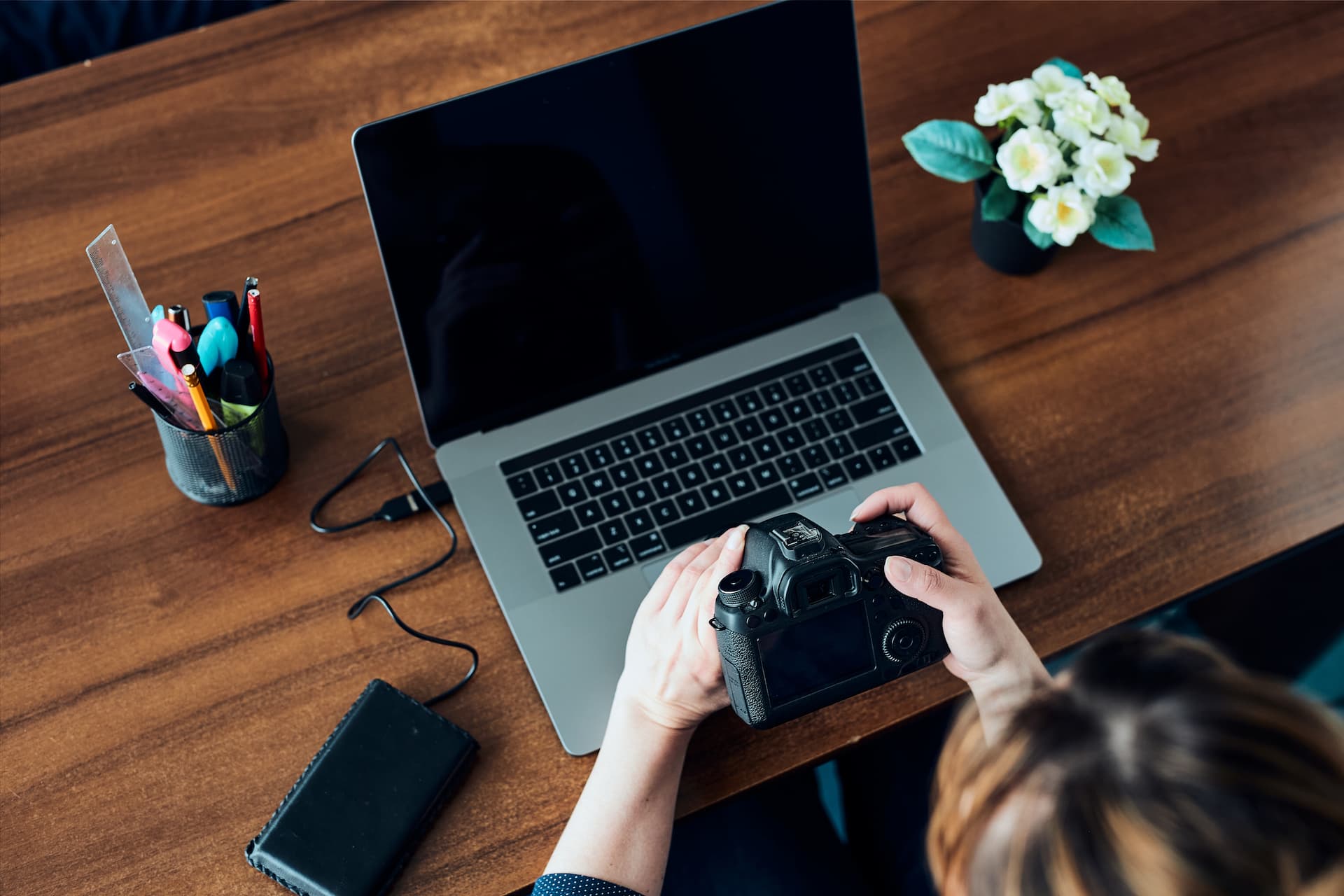 Female photographer working on photos on laptop and camera. Woman editing retouching browsing photos