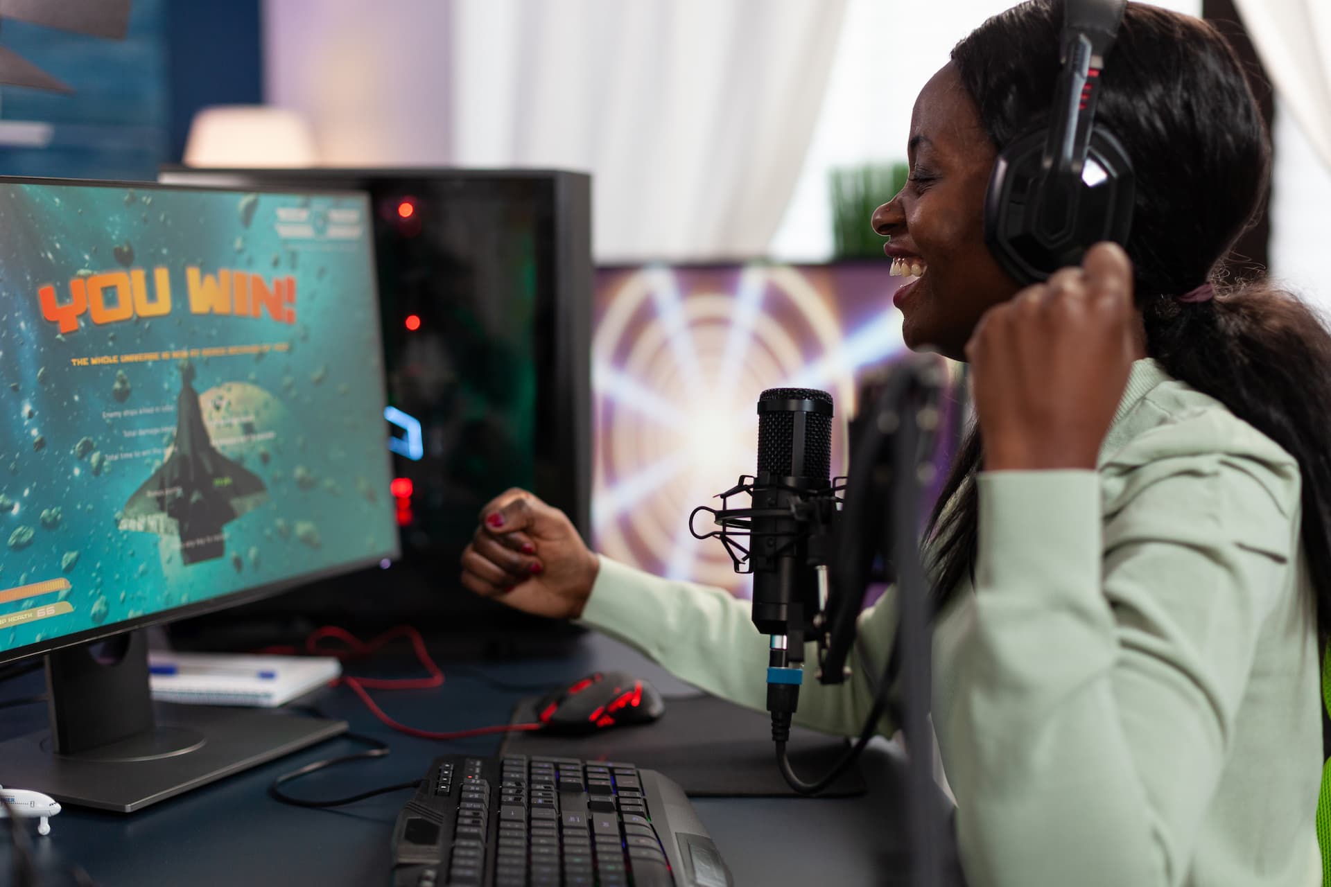 Happy cyber woman winner sitting at gaming desk playing
